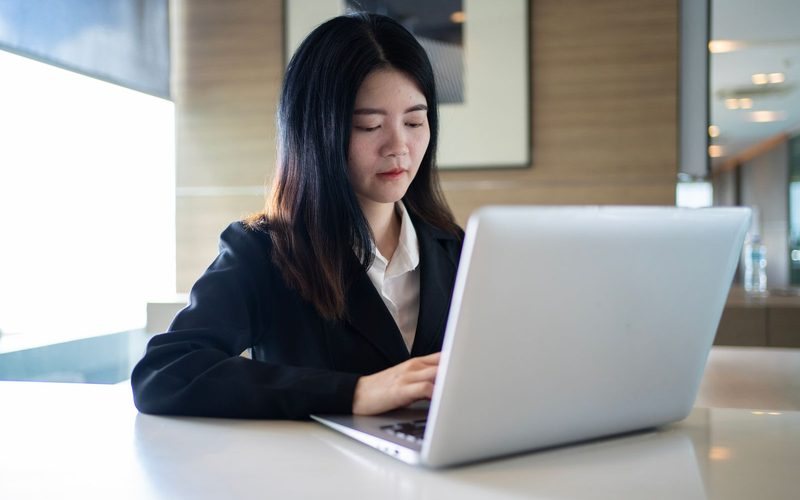 Junge Frau arbeitet im Büro am Laptop