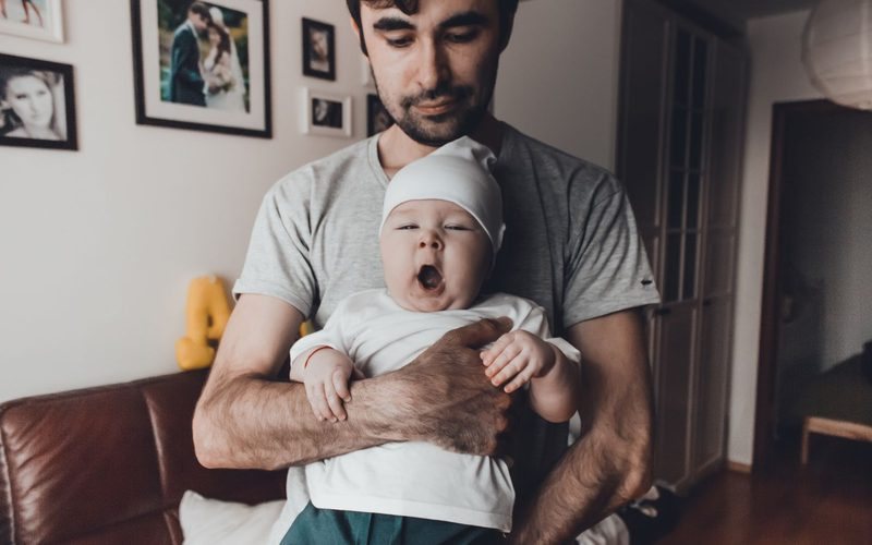 Vater hält sein gähnendes Baby im Arm