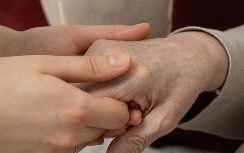 Junge Hände halten die Hand eines älteren Menschen